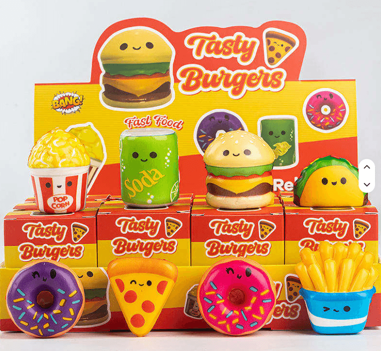 PU food squishy assortment with smiling burger popcorn soda taco pizza donuts and fries beside individual boxes and a countertop display